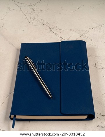 Blue notebook and a metalic pen on it,