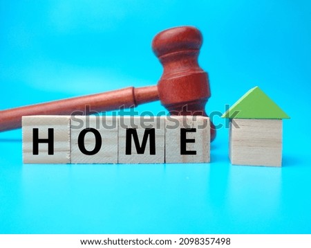 Gavel and wooden cube with word HOME on blue background.