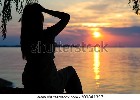 silhouette of a girl in a dress on the beach at sunset
