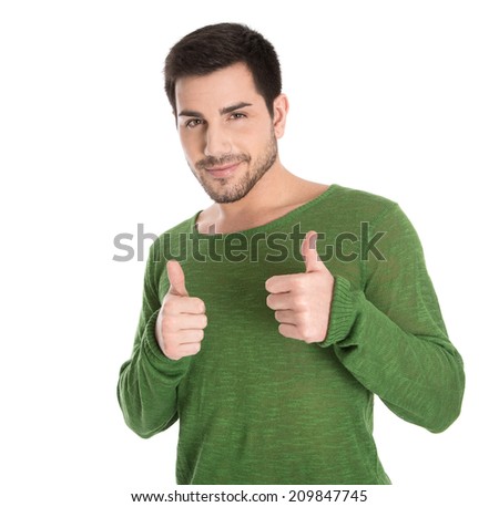 Happy isolated young man in green pullover making thumb up gesture.