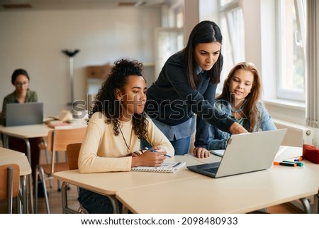 IT teacher and her students using laptop during computer class in high school.  Royalty-Free Stock Photo #2098480933