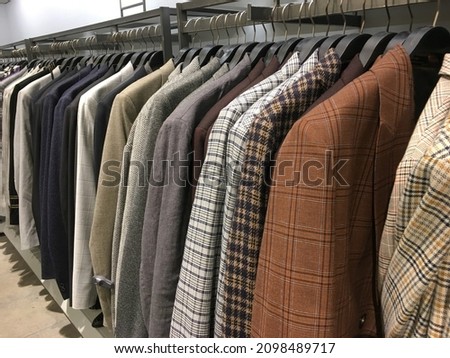 Mens fashion row of suits in different colors 
on hanger in a retail clothes store
