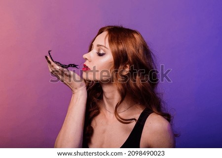 Beautiful seductive fashion redhead female with make up with a scorpion in a studio