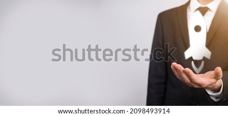 Startup business concept, Businessman holding tablet and icon rocket is launching and soar flying out from screen with network connection on dark background