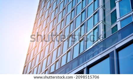 Commercial building close up in blue tone. Gigantic skyscraper from below. Architecture details of modern building amd glass facade. Business background on a beautiful sunny day. 