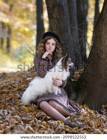 Blonde girl with a small dog in the autumn forest
