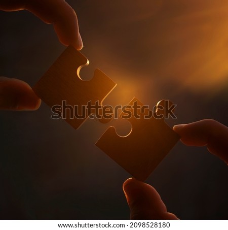 two hands of businessman to connect couple puzzle piece with sky background.Jigsaw alone wooden puzzle against sun rays.one part of whole.symbol of association and connection. business strategy