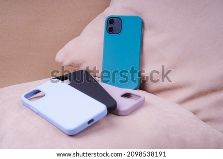 Four silicone smartphone cases. Protective smartphone cases in black, beige, blue and colors. A set of silicone cases for smartphone. Pastel colors. Smartphone in a turquoise silicone case. Royalty-Free Stock Photo #2098538191