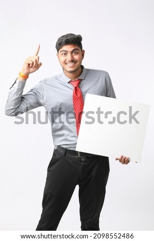 Young Indian business executive showing blank sign board over white background.