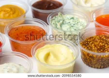 Variety of different sauces and condiments in small cups on white table. Mayonnaise, cheese sauce, pesto, mustard, sweet and sour sauces. Royalty-Free Stock Photo #2098554580