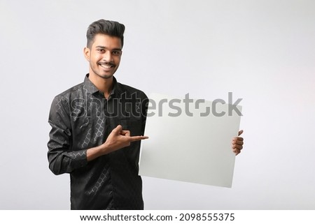 Young Indian college student showing blank signboard on white background.