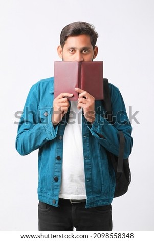 Young Indian college student holding diary in hand on white background.