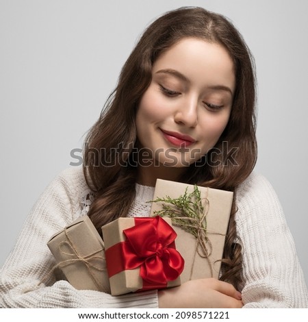 Happy girl in a sweater holds three gifts for Christmas or New Year