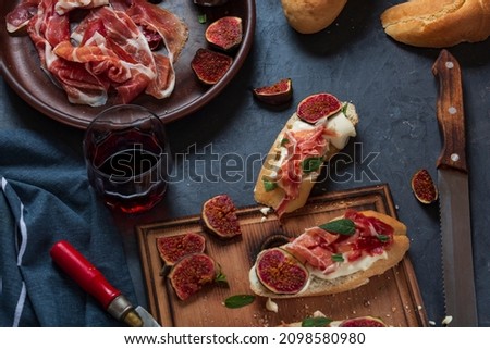 Sandwiches with cream cheese and jamon, close-up spanish appetizers with wine