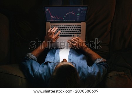 Young business man trader analyst looking at laptop monitor on sofa, investor broker analyzing indexes, financial chart trading online investment data on cryptocurrency stock market graph. Top view Royalty-Free Stock Photo #2098588699
