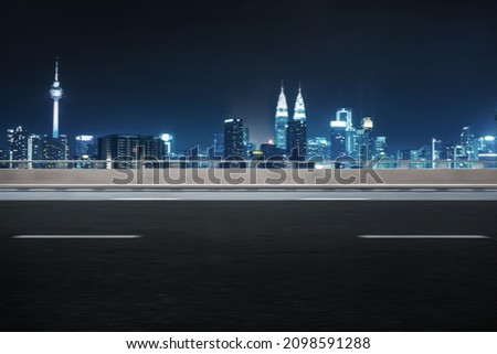 Motion blur effect, side angle of highway overpass with city skyline background. Night scene.