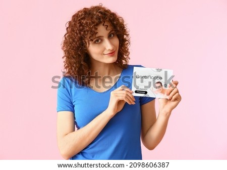 Pretty young woman with gift certificate on pink background