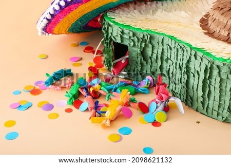 Mexican pinata in shape of avocado, sombrero hat and confetti on color background, closeup