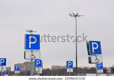Signs for parking cars of people with disabilities on the background of lighting poles and gray sky