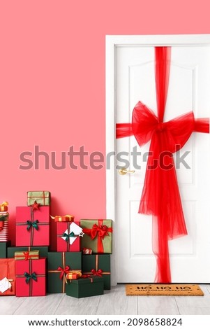 Decorated white door and Christmas gifts near color wall