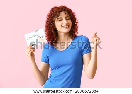 Happy young woman with gift certificate on pink background