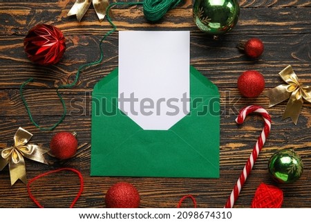 Envelope with blank card and Christmas decor on dark wooden background