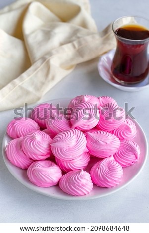 Small pink meringues in a white dish. Macro shot. Vertical view