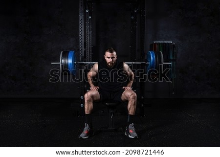 Young active strong sweaty muscular fit man with big muscles preparing for hardcore benchpress workout cross training with heavy barbell weights in the gym. Male concentrated sitting on the bench. Royalty-Free Stock Photo #2098721446