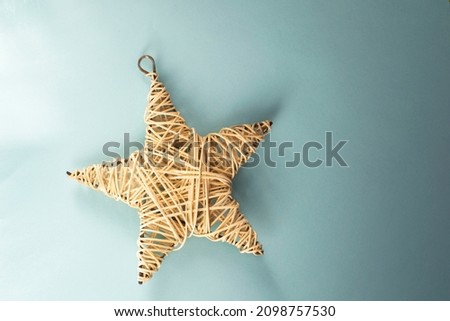 Banner with rattan star on blue background. Christmas picture with free space for text. Natural wooden rattan star. Light blue new year card.