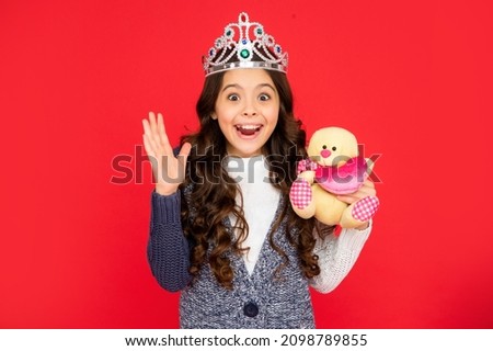 amazed happy child in queen crown. princess in tiara. kid hold bear toy.