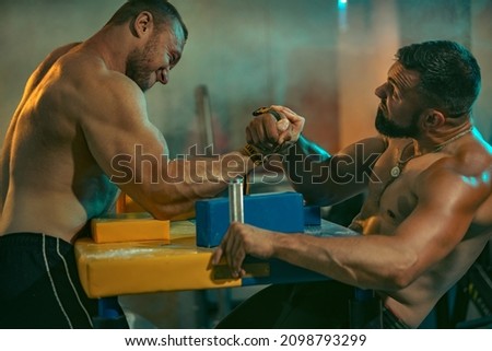The Armwrestling. Two strong athletes in the gym compete in arm wrestling. Bodybuilders armwreslers in athletic training room