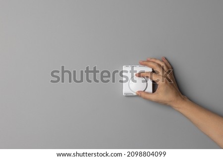Woman Hand Adjusting or Turning On  Off Wall Temperature Regulator Controller Button  Royalty-Free Stock Photo #2098804099