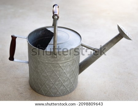 A traditional metal watering can sitting on the patio 