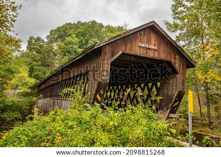 The State Road Covered Bridge crosses the West Branch of Conneaut Creek during the Autumn leaf color change in Ashtabula County, Ohio.