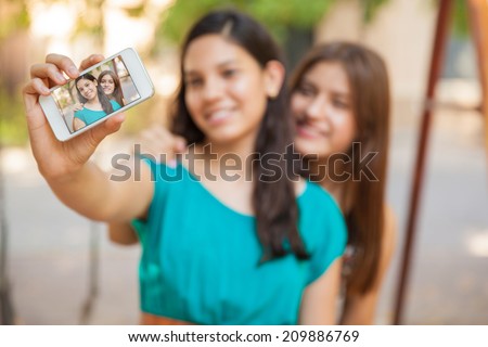 Pretty teens taking a selfie with their phone. Focus on smart phone