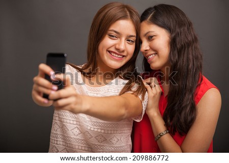 Pretty Hispanic teenage friends taking a selfie with a smart phone