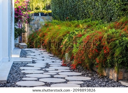 Round white marble walkway with black gravel in the garden of a house with tropical vegetation. Landscaping concept. Royalty-Free Stock Photo #2098893826