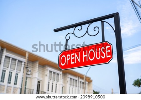 Open House sign in front yard next to a large house. For rent sign as a symbol of private property renting. for rent sign on a red background. Concept. rental a private house. Renting a country house.