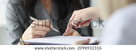 Lawyer pointing to insurance contract showing client to woman where to sign. Sign a purchase agreement at a meeting concept