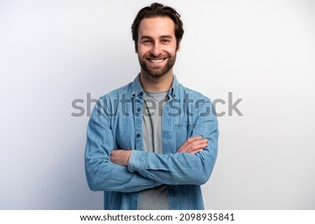 Image of happy brunette man wearing basic clothes smiling at camera with hands crossed isolated over white background. Stock photo 
