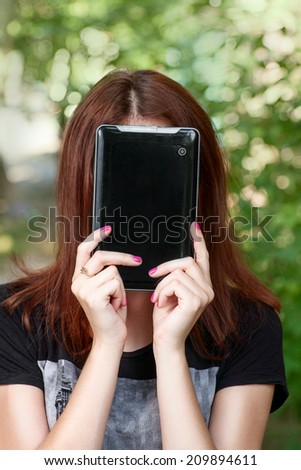 Redhead women hide her face by tablet PC.