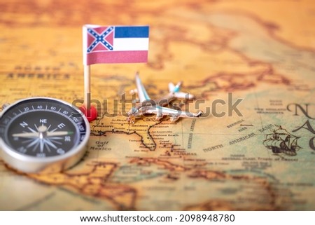 Mississippi flag, airplane and compass on the map of the old world. The concept of domestic tourism and recreation in America.