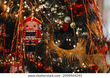 Retro festive Christmas toy Nutcracker and New Year golden decorations hanging on the Christmas tree. Winter holiday decor, New Year winter details