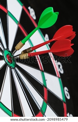 Concept of competition and goal achievement.Achieving goals in business and life.Dartboard with three darts stuck right center of target