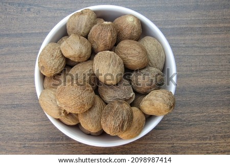 Nutmeg in a bowl on wooden background