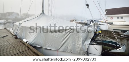 Sailboat moored to a pier in a yacht marina. Stavanger, Rogaland region, Norway. Transportation, nautical vessel, sport, recreation, service, winterization Royalty-Free Stock Photo #2099002903