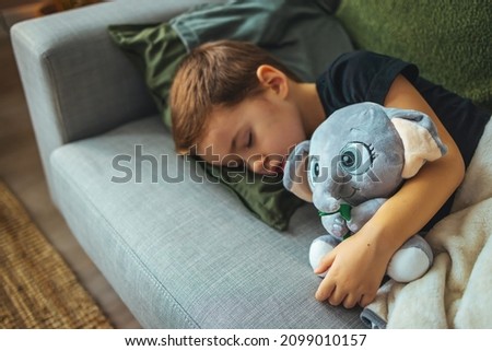 Photo of little boy sleeping together with elephant. His favorite napping spot. Adorable kid boy after sleeping in bed with toy. Boy sleeping on bed with elephant. Sleepyhead.