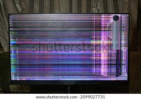 one rectangular monitor with a cracked screen and colored stripes stands in the room