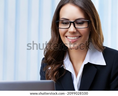 Portrait image of smiling businesswoman in black suit and spectacles, working with laptop computer at office. Success in business, job and education concept. skype zoom video conference