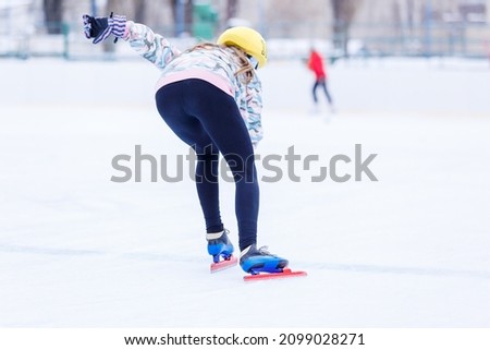 Slim teenage girl skating on the ice track on short treck training.